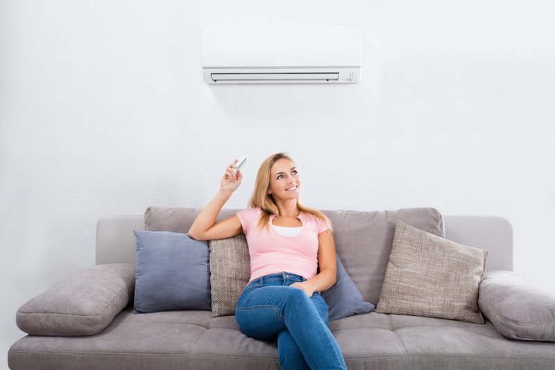 Woman sitting comfortably on couch in air conditioned room.